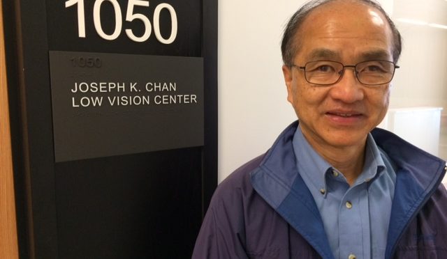 Joseph Chan next to the Low Vision Clinic bearing his name
