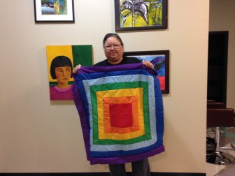 Molly Irish holds a rainbow square of the Memory Quilt