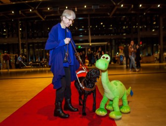 a woman and her dog inspect a dinosaur plush doll