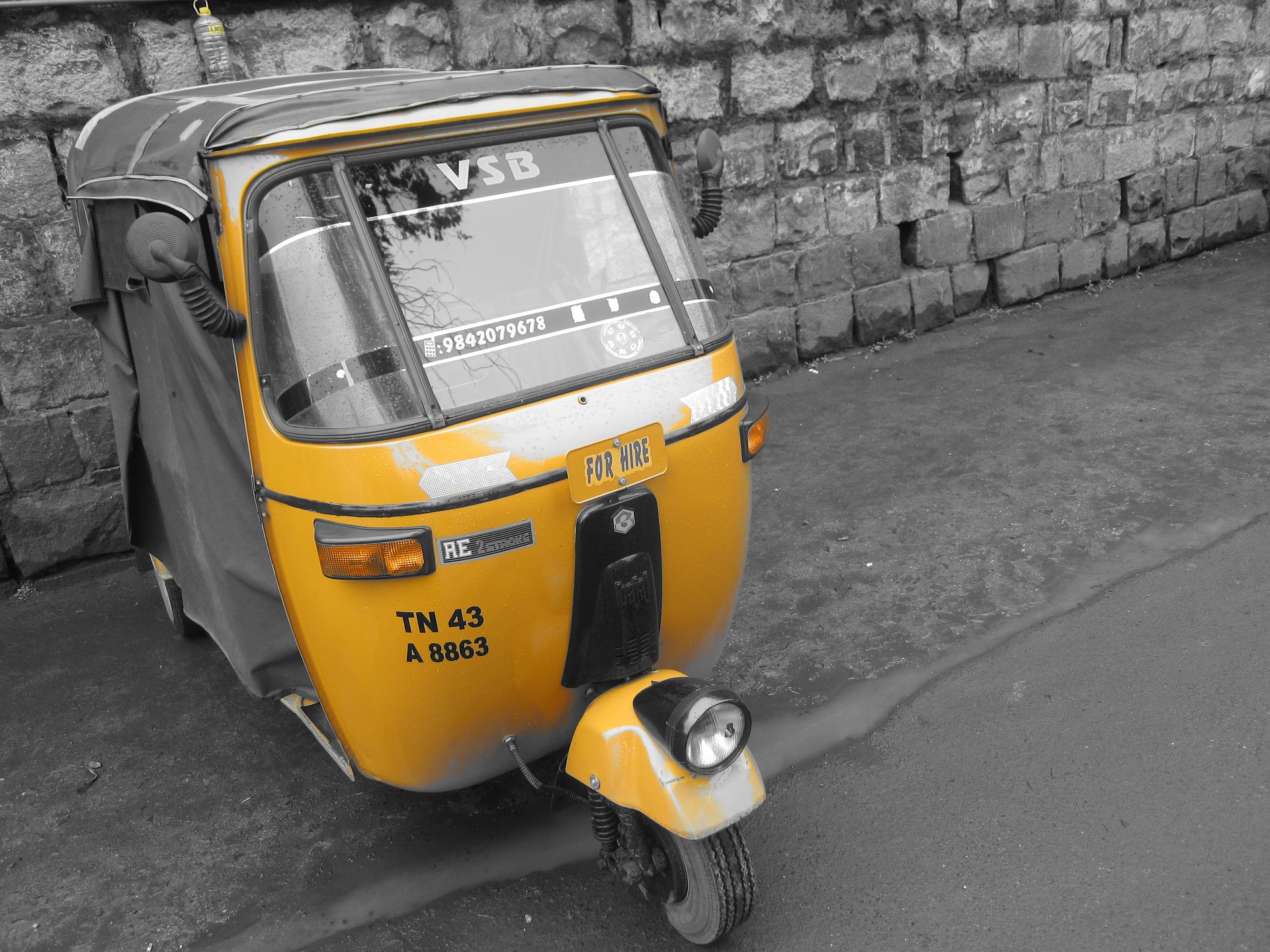 image: a yellow auto-rickshaw with a reflective winshield