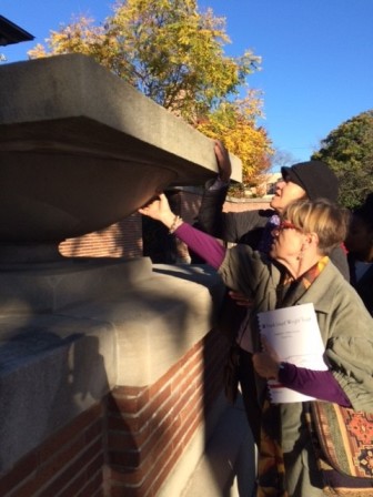 Visitors touch a planter in the form of Wright’s logo- on the exterior wall of the yard of Robie House.