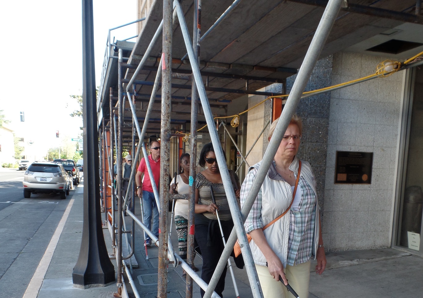 Students newer to Orientation & Mobility training took to the streets of downtown Napa utilizing the new cane skills they learned throughout the Immersion week. Here the group maneuvers under scaffolding set up around buildings that were damaged during the recent Napa earthquake. 