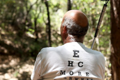 Older man facing away, t-shirt reading ‘EHC More’ styled like eye examination chart.