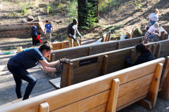 Volunteers sand the Redwood Grove benches at EHC in preparation for treating the wood.