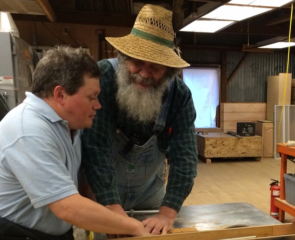 George Wurtzel teaches student Brian Buhrow how to cut wood.
